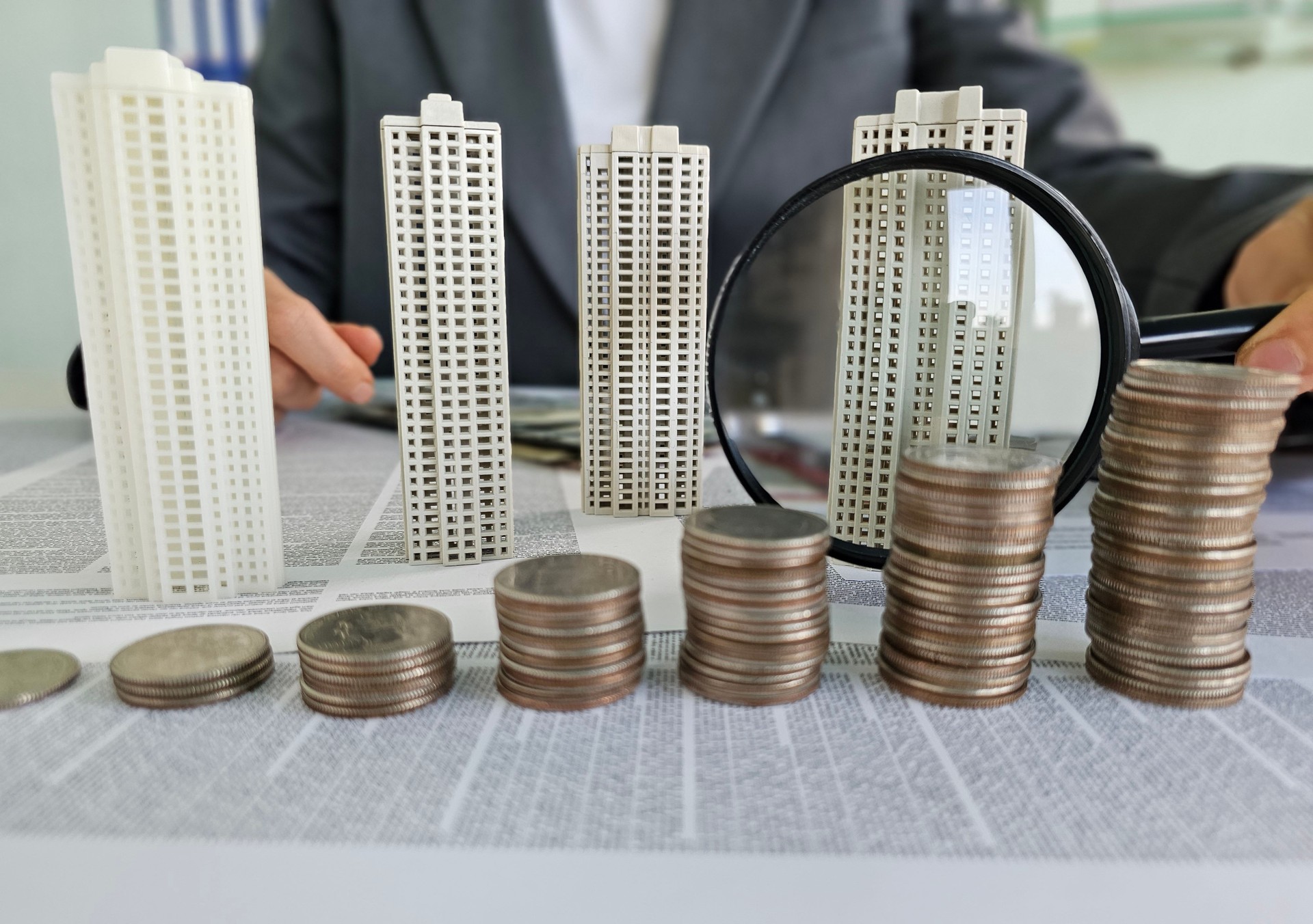Los edificios esculpidos y las monedas simbolizan el análisis de la inversión inmobiliaria y el concepto de estrategias de crecimiento financiero